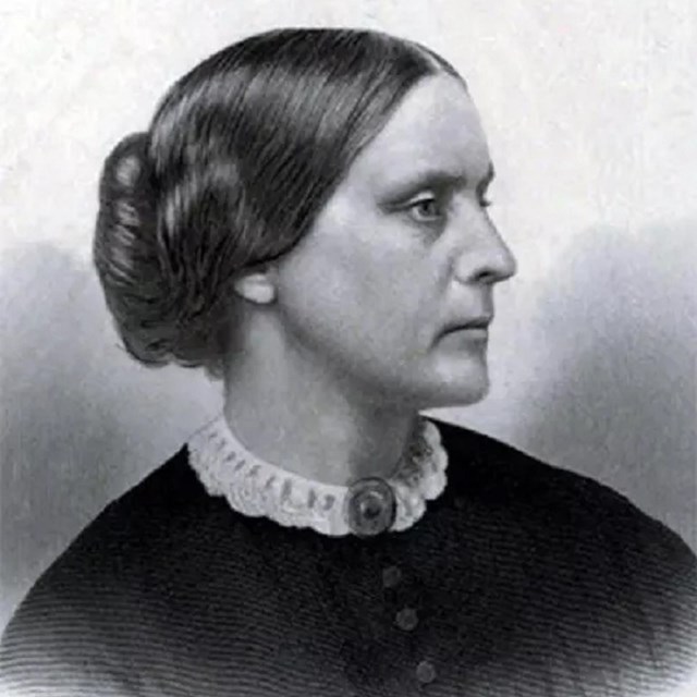 A young Susan B Anthony looks to the right the camera wearing a dark dress and white collar