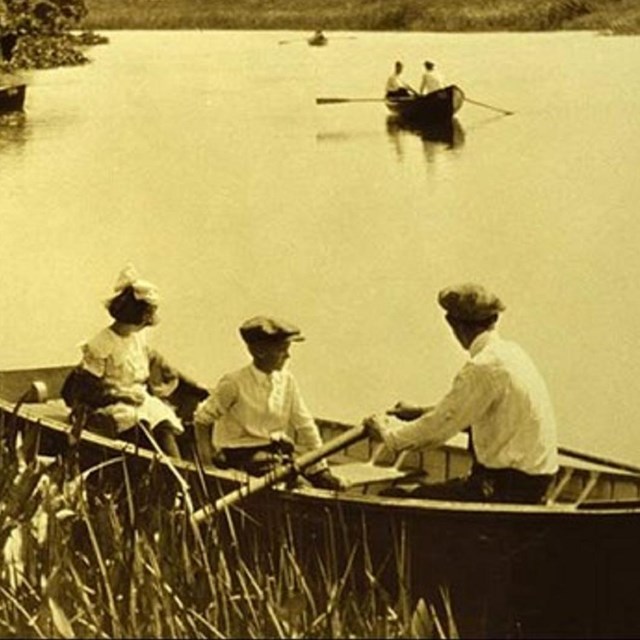 Photo of adult and t children in a boat on a pond. 