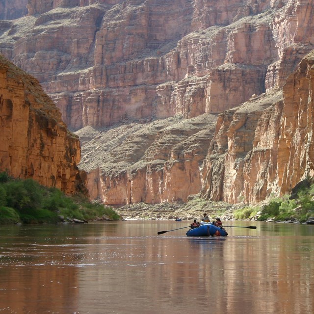 Photo of a raft floating down the river in a steep sided canyon.