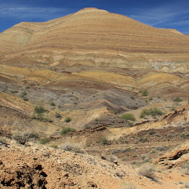 Photo of a desert hillside with exposed rock layers.