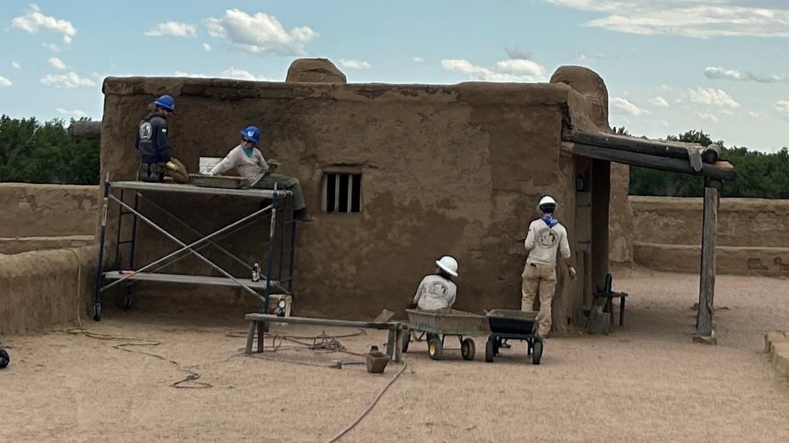 A youth crew works on repairing an adobe wall
