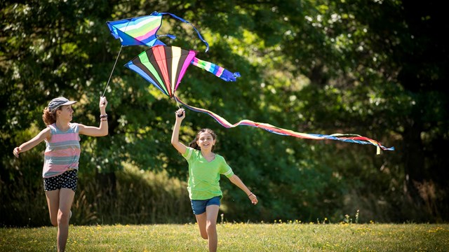 Two girls running with kites