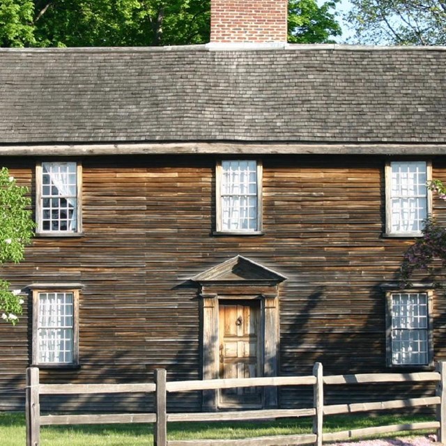 The John Adams Birthplace in Spring, a dark wooden house. 