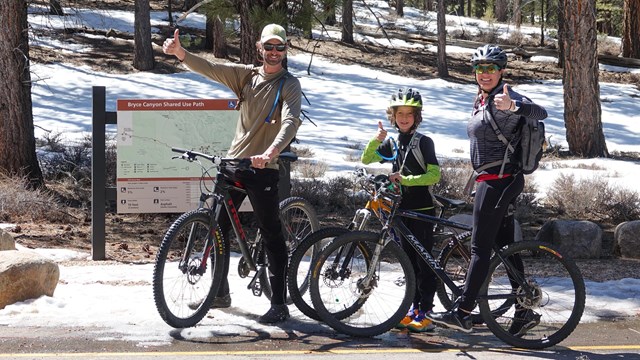Three visitors on bikes give a thumbs up to the camera.