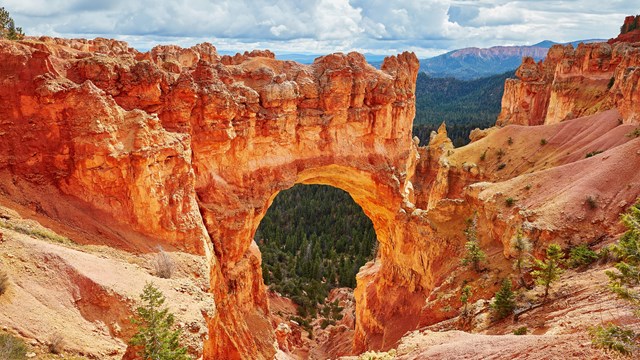 A red rock formation creates a bridge formation. 
