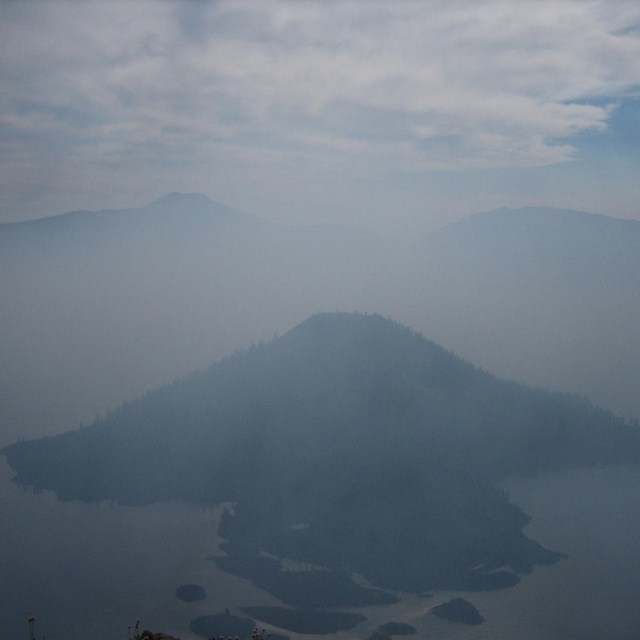 The Crater Lake Caldera is filled with smoke obscuring Wizard Island. 