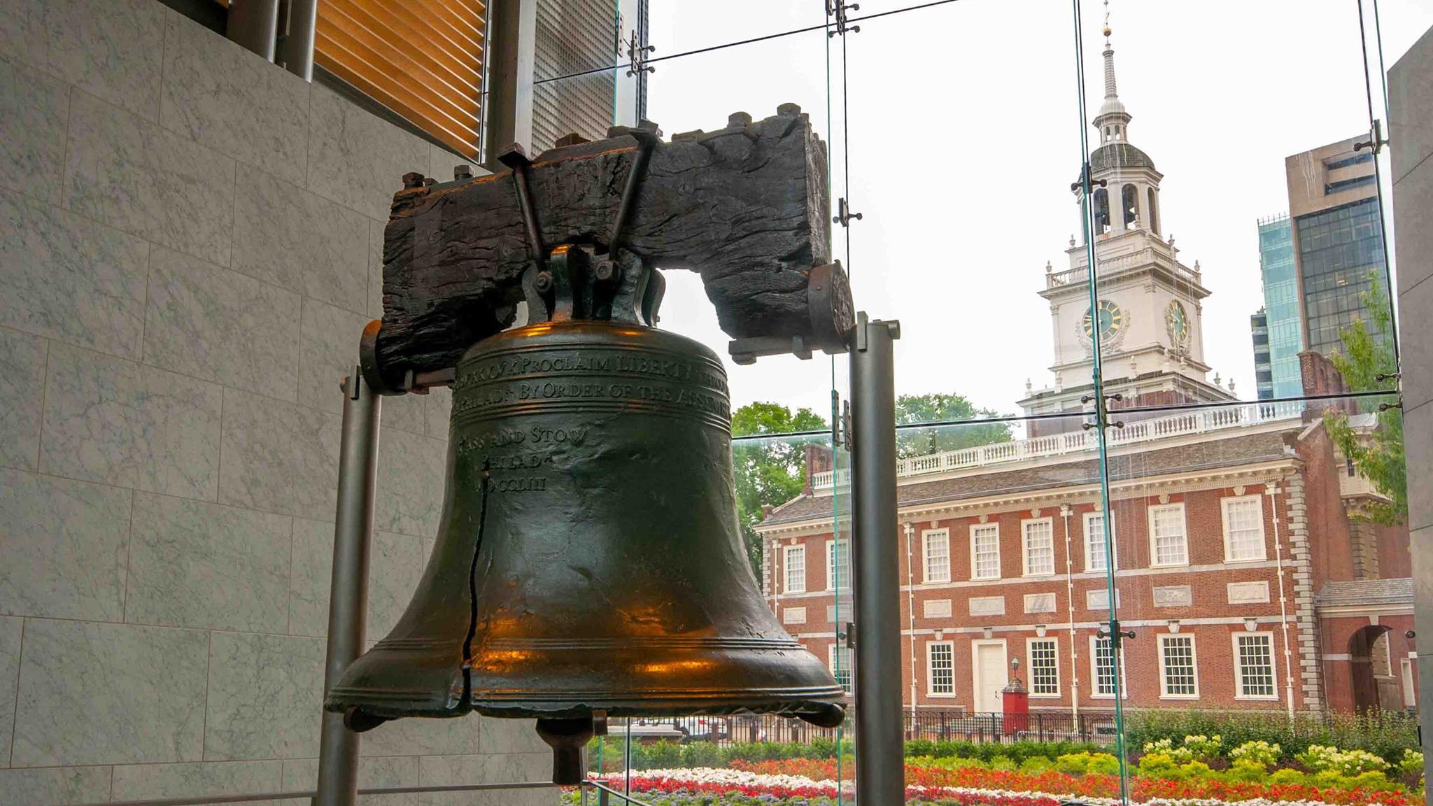 Liberty Bell in front of a window revealing Independence Hall