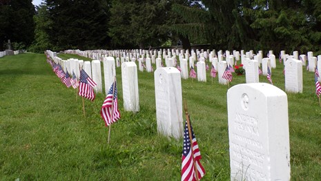 A row of white headstones with American flags in front
