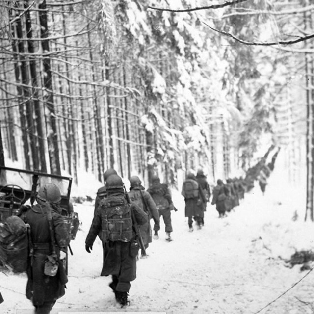 A black and white image of soldiers marching in a snowy forrest