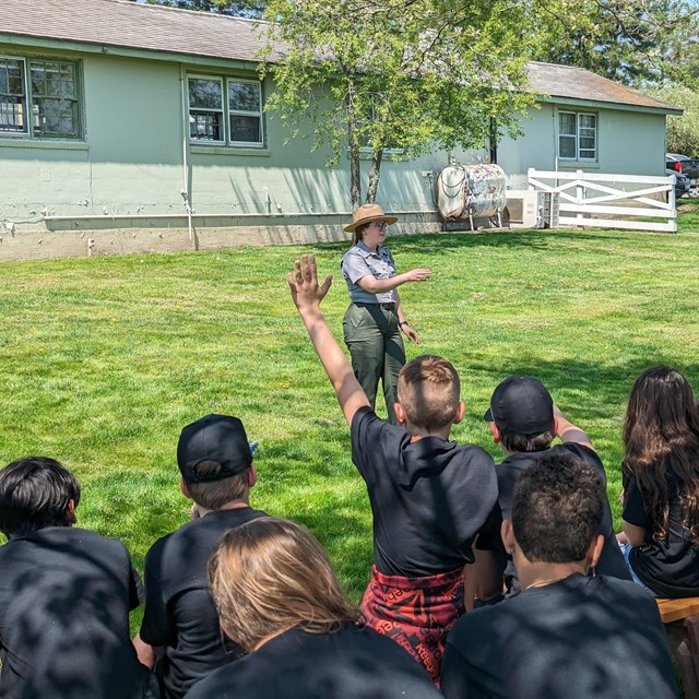 A park ranger speaks to a group of students on a sunny day