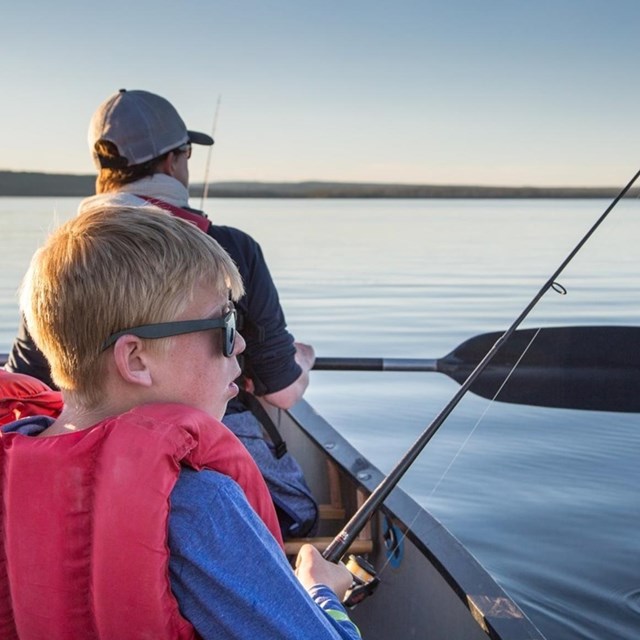 Child fishing on boat with life jacket. 