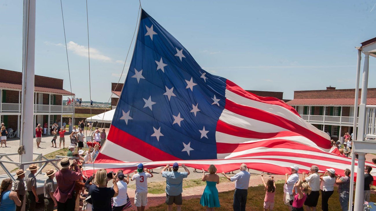 A picture of people holding the Garrison Flag in the parade ground.
