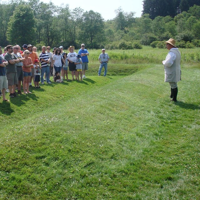Ranger in period dress addressing a crowd of visitors