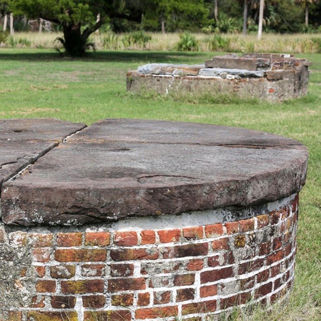round brick cistern with grass trees and another brick cistern in the distance