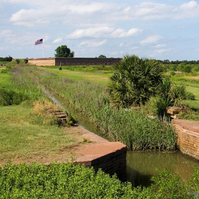 brick work along canal view of American flag and fort in background