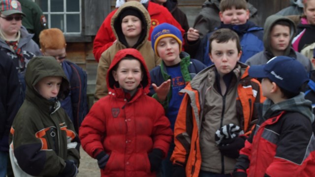 A group of young kids stands grouped together in jackets. 