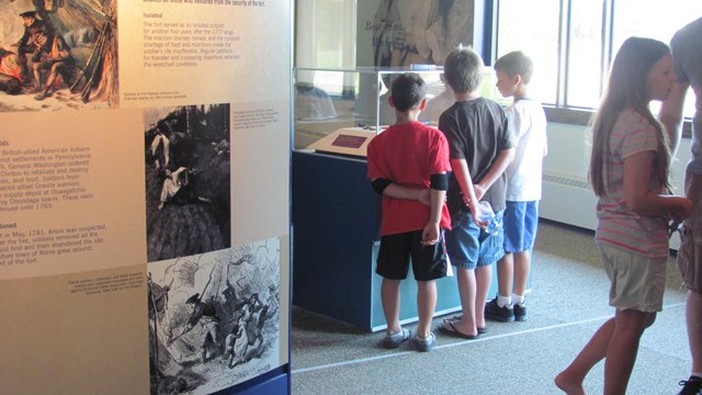 A group children look at museum cases.