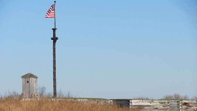 A flag waving over the walls of the fort, as viewed from a distance. 