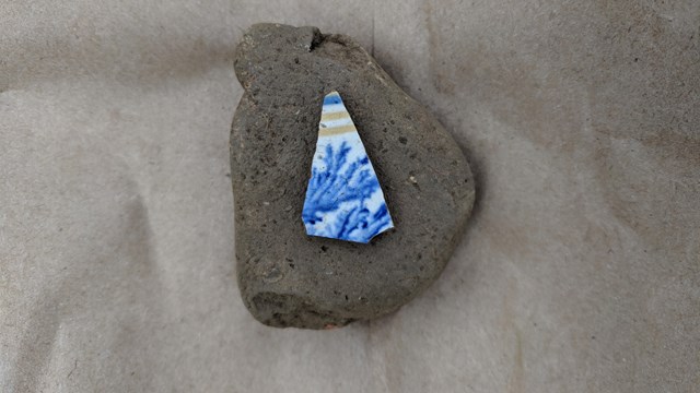 A small fragment of blue, yellow, and white ceramic.