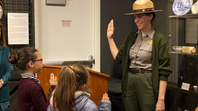A national park ranger swears in two new junior rangers at the Visitor Center.