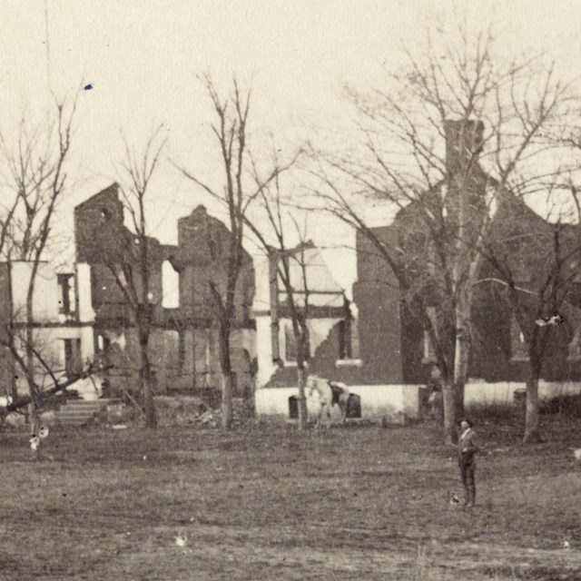 Historical photo of a large house with battle damage.