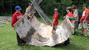 Boy scouts preparing birch bark to make a teepee