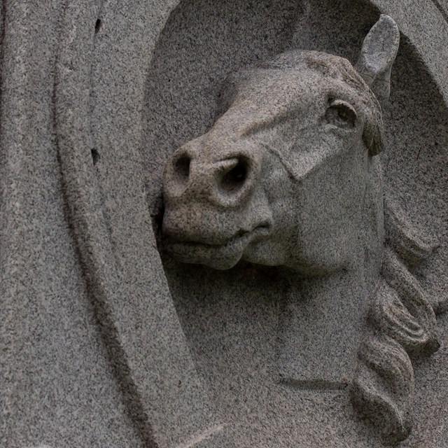 Close up of a monument with a granite horse.