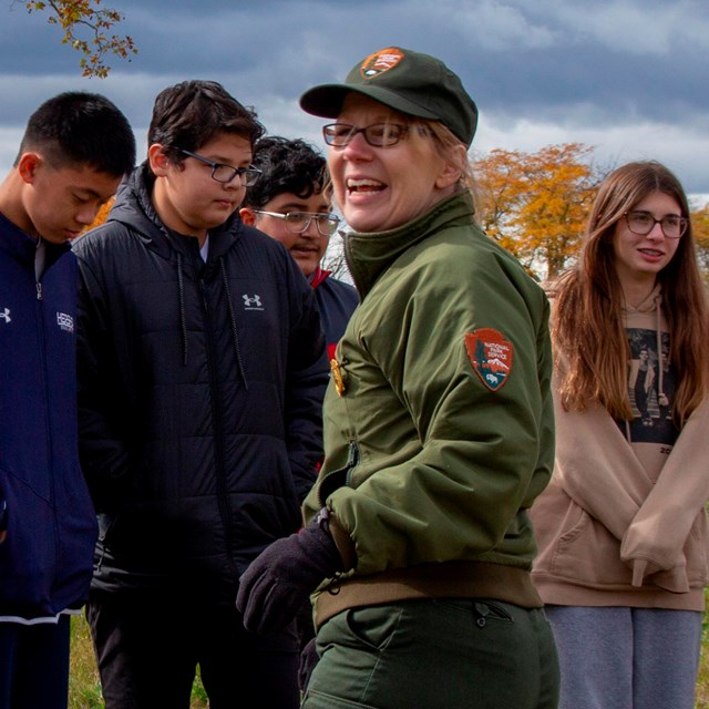 A Park Ranger smiling as a group of students listen.
