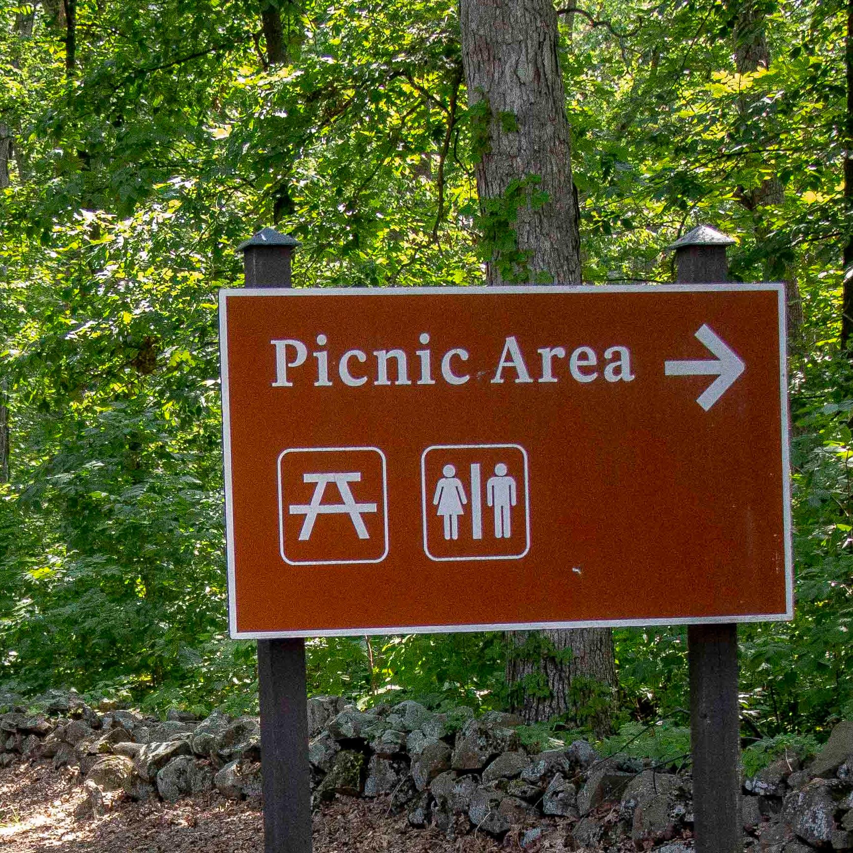 A brown metal sign with an arrow pointed right that reads 