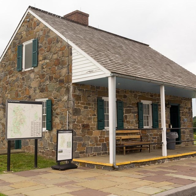 Stone building with four white pillars and a front porch with park maps to the left.