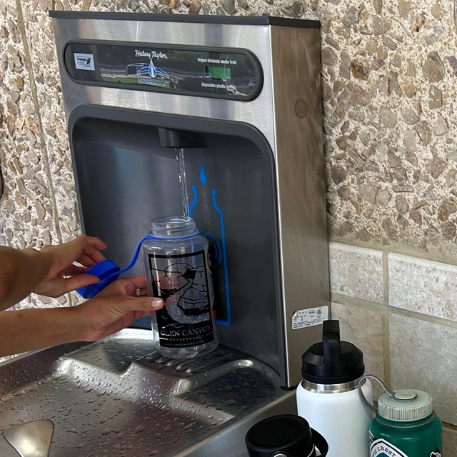 a water bottle filling station is used to refill a few water bottles