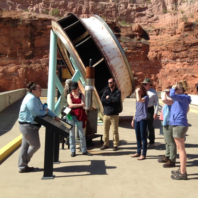 Group gathers around a tour guide at the top of Glen Canyon Dam