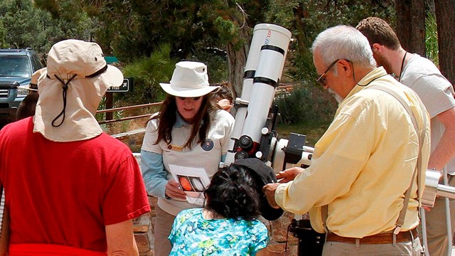 volunteers help visitors view the sun through a solar telescope.
