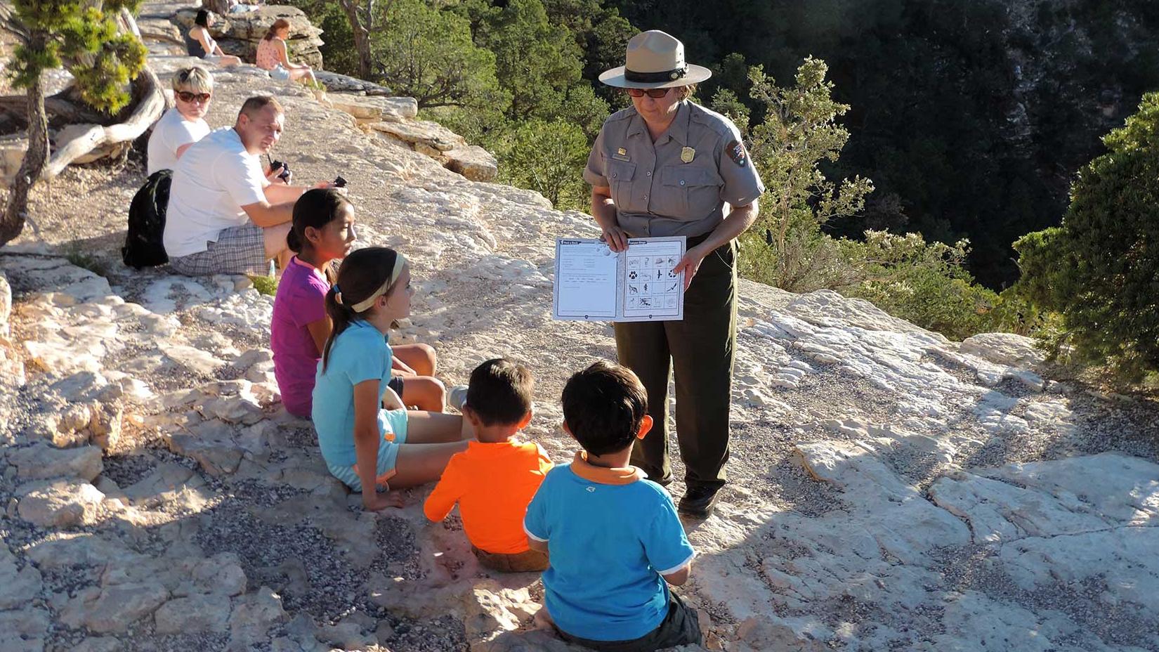 A ranger helps a group of four kids with there Junior Ranger book.