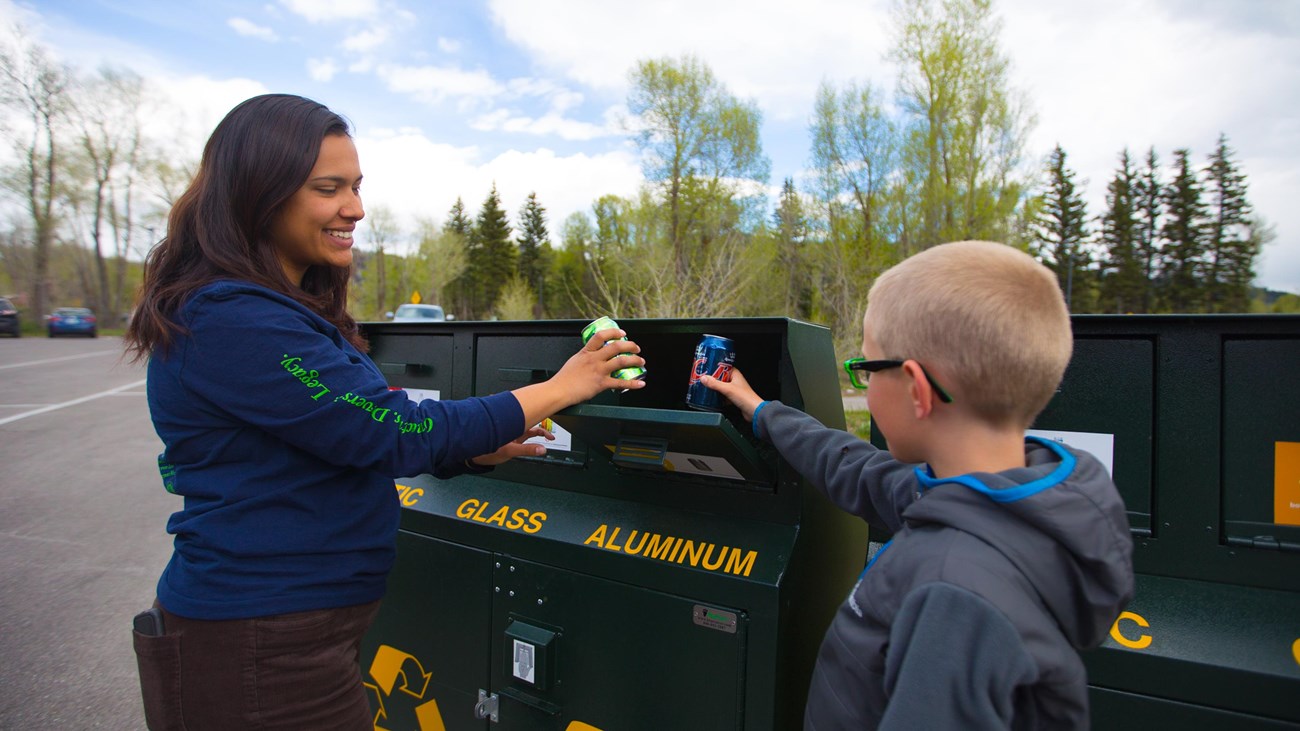 Visitors depositing recyclables in a green recycle bin.