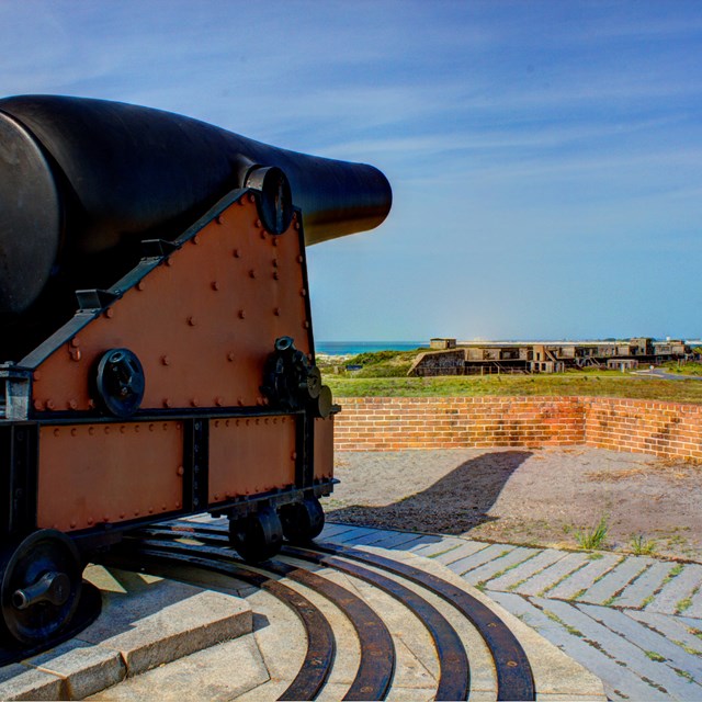 Large cannon sits atop a historic fort.