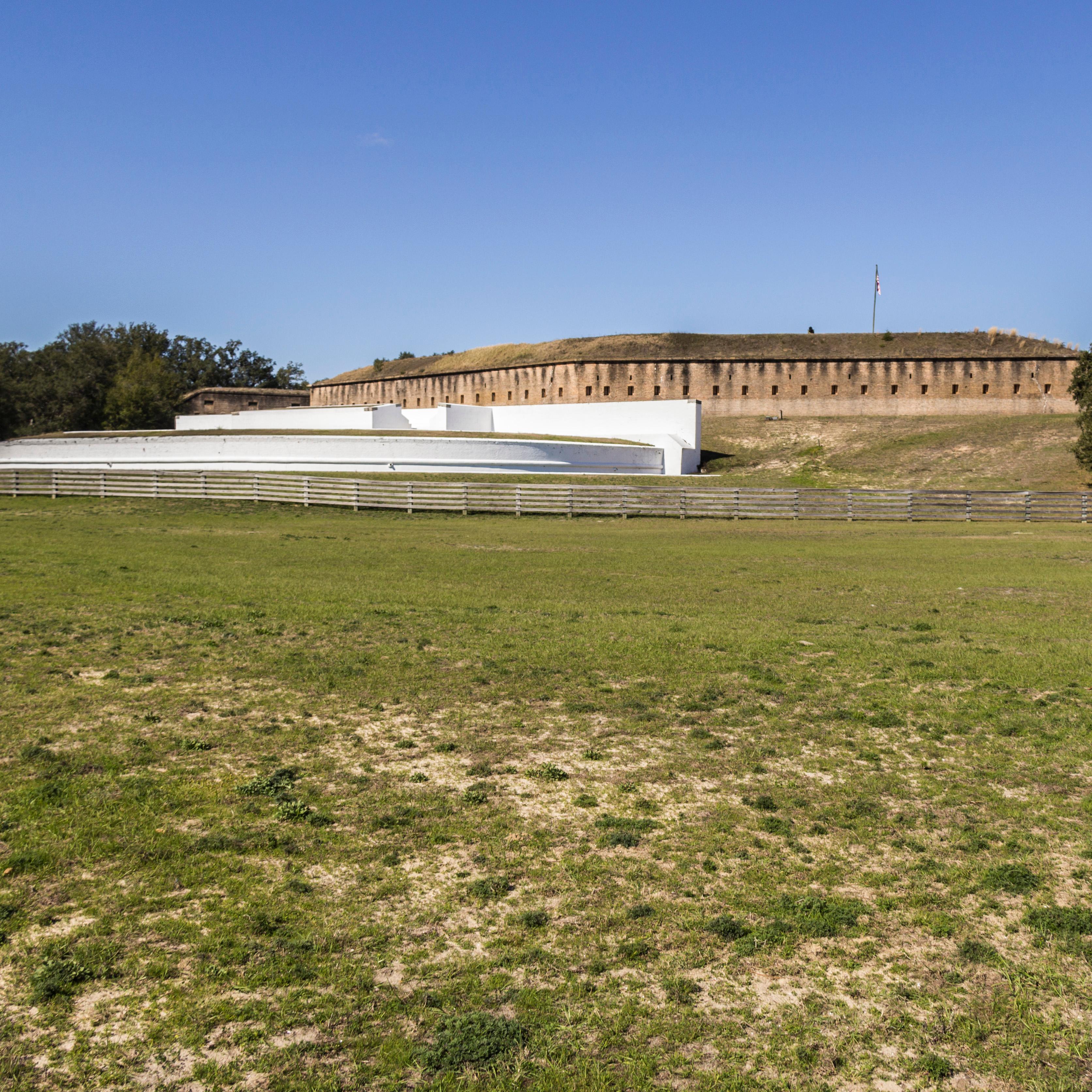 A large masonry fort sits on a hill above a white painted fort.
