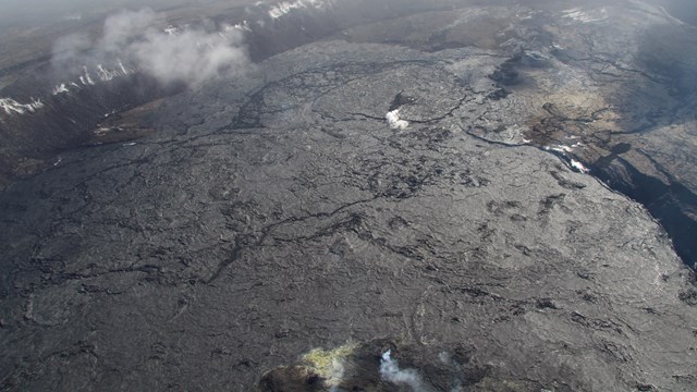 A volcanic cinder cone emitting steam. 