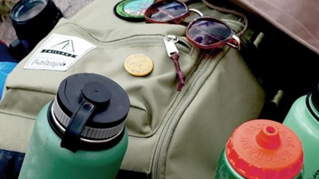 A backpack, water bottle, hat, sunglasses, camera, and sunscreen. 