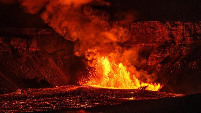 Molten lava erupting from a crater at night. 