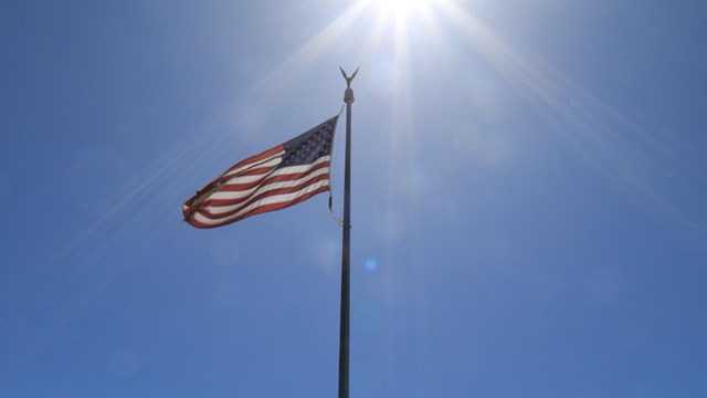 US flag backlit by a blinding sun.