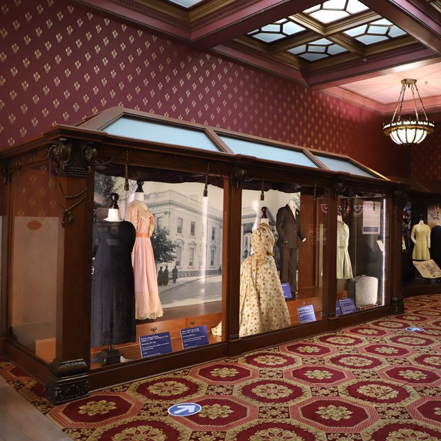 Museum exhibit of dresses in a glass case