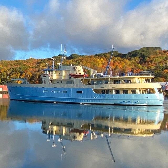 A large blue and cream colored motor vessel at dock.