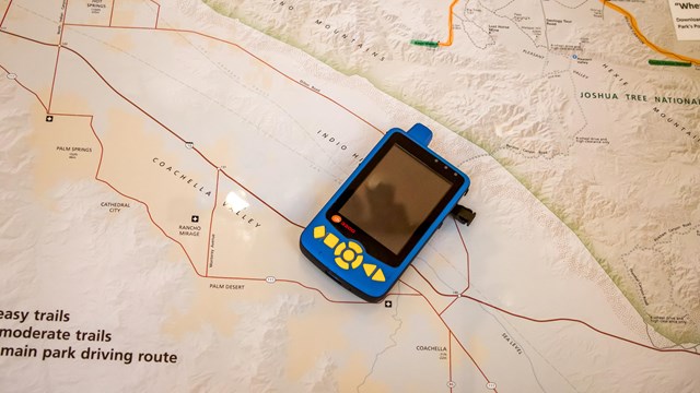 An audio description device lays on a map.