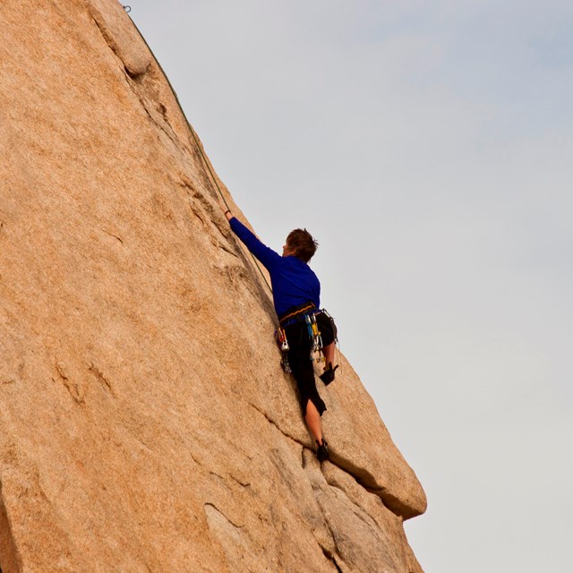 a climber climbs up a steep rock face