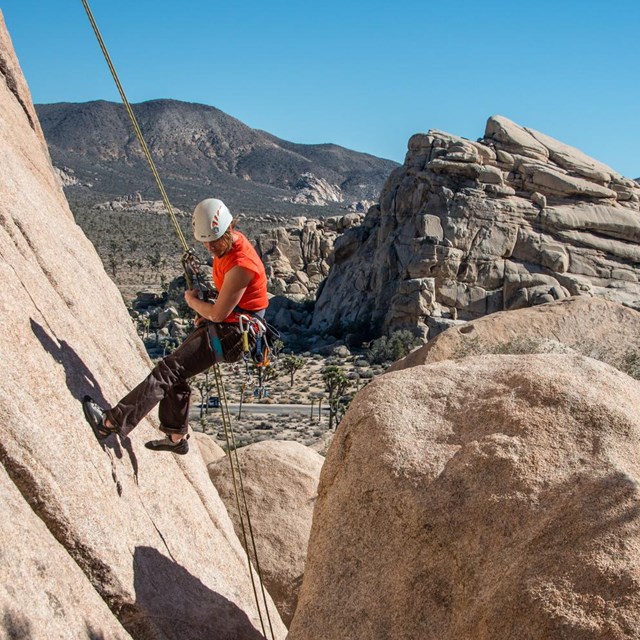 a climber rappels down a steep rock face