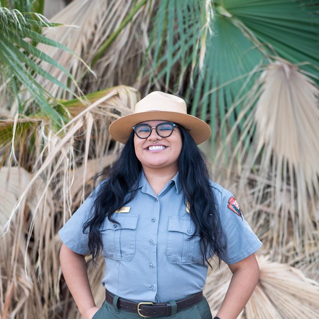 a ranger smiling in front of palm fronds 