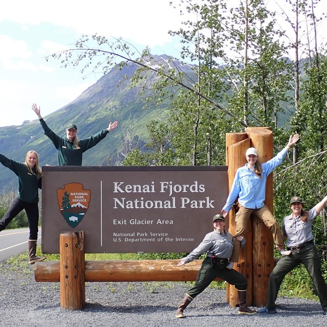 Five park staff pose with the Kenai Fjords National Park sign.