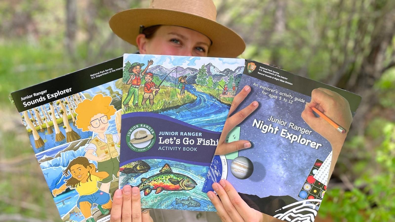 Several kids hold up junior ranger program materials
