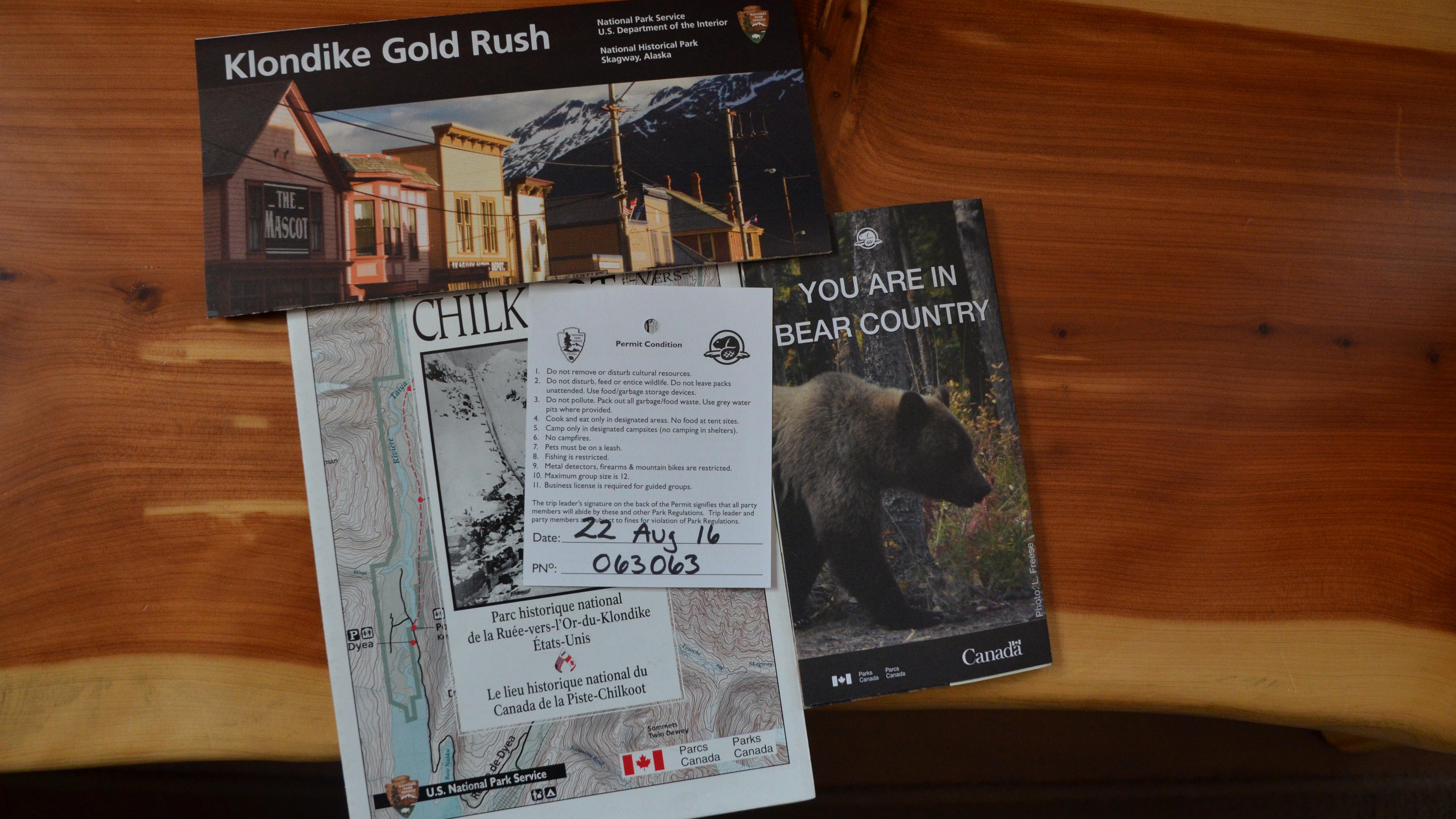 Brochures and a hiking permit on a wood surface